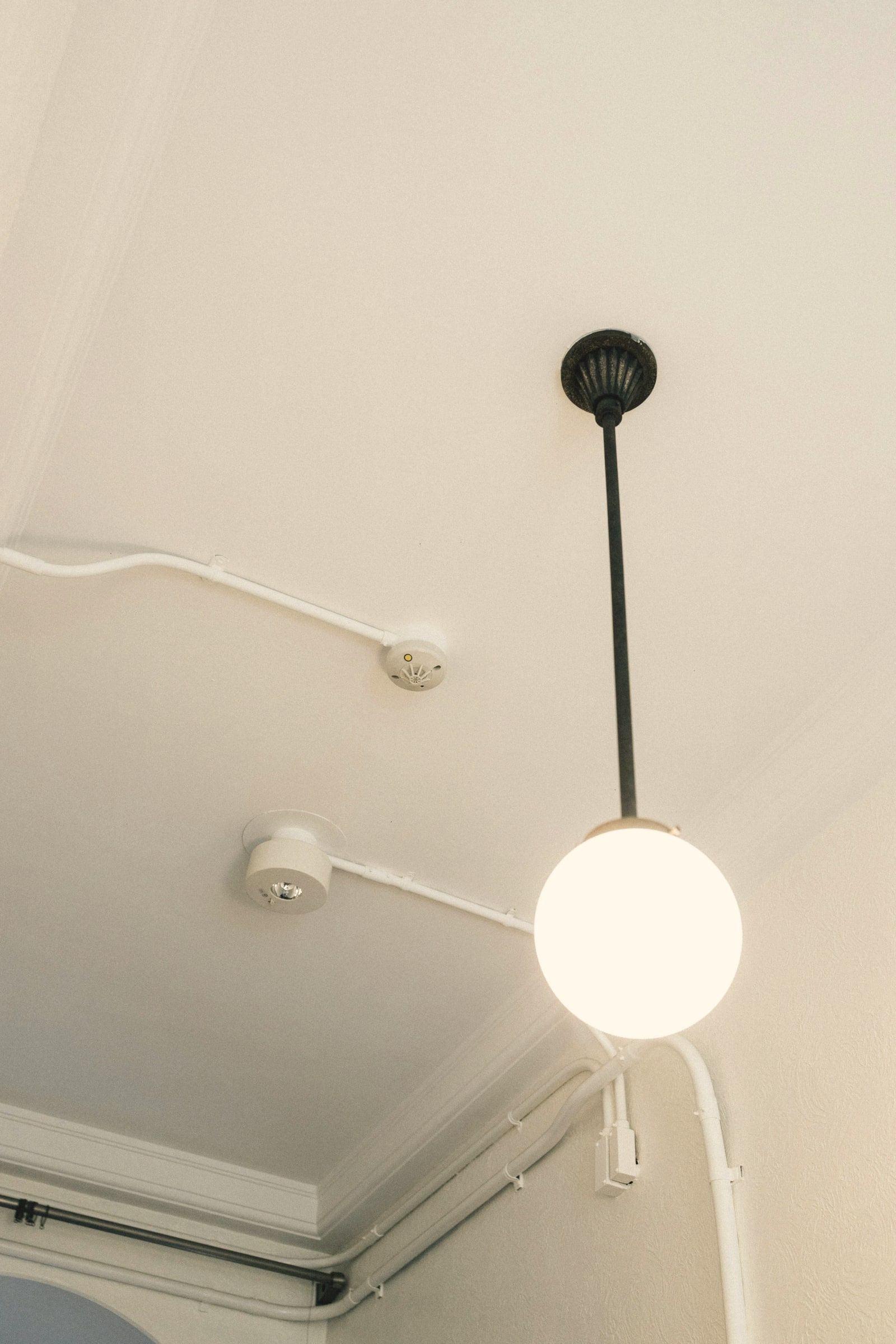 Smoke alarm on the ceiling of an older apartment, next to a pendant light